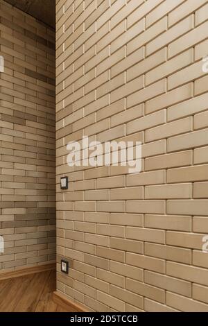 part of the wall decorated with artificial bricks of light beige color Stock Photo