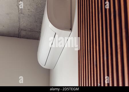 air conditioner on a white wall decorated with dark brown wooden slats bottom view Stock Photo