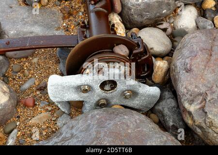 A whole rear axle from a wrecked car on the seashore amid the rocks at this beauty spot in south Wales. Stock Photo
