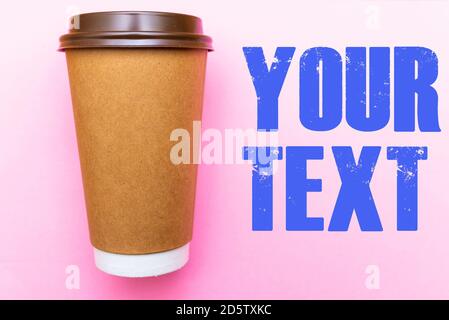 brown paper coffee cup on a bright pink backgroud. Simple flat lay with copy space. Minimal concept. Stock Photo