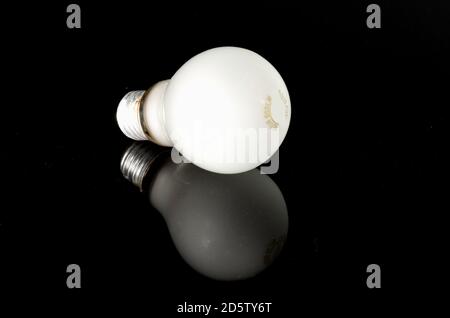 Frosted light bulb on reflective black surface. Conceptual image of thought process with successful inspirational result. Bright idea from reflective Stock Photo