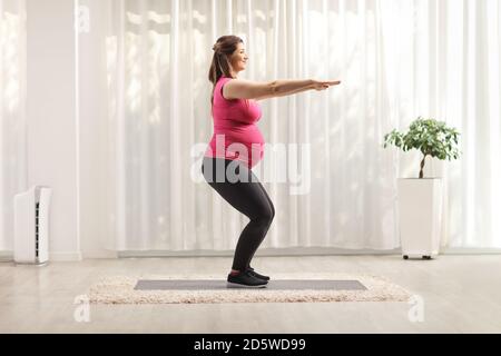 Full length profile shot of a woman doing pregnancy exercises at home on a mat Stock Photo
