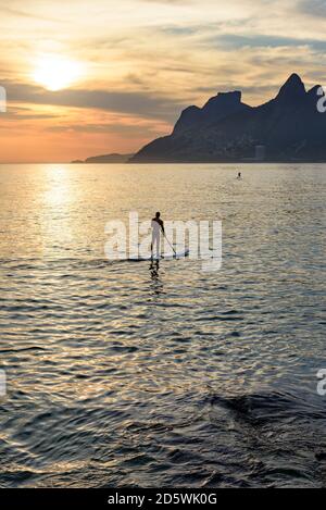 Stand up paddle at Arpoador beach in Ipanema during sunset Stock Photo