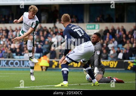 Millwall's Jordan Archer makes a save from and Barnsley's Cameron McGeehan Stock Photo