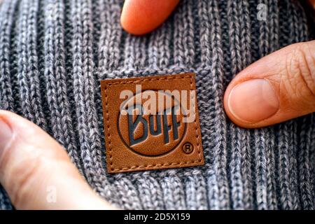 Tambov, Russian Federation - November 16, 2019 Woman hands showing clothes label Buff on gray knitted hat. Stock Photo