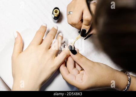 Top view of crop stylish painting nails of female client over table in salon Stock Photo