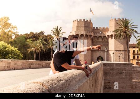 Young couple sightseeing in Valencia with cloth masks to protect from the virus. Tourism concept during the coronavirus in Spain. Stock Photo