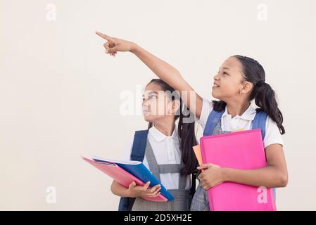 Girl pointing her finger for her friend to see. Girls at school with notebooks and folders in their hands. Copy space for text. schoolgirl showing som Stock Photo