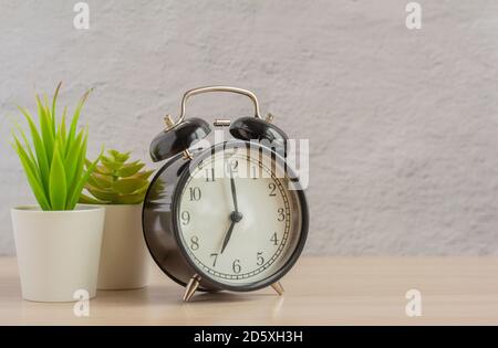 Vintage alarm clock in black on a table or shelf against the wall.Copy of the space. Stock Photo