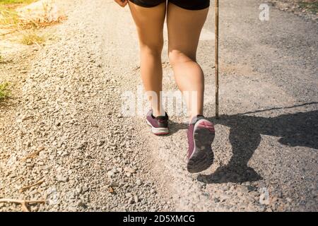 Young fitness woman hiker legs at rural trail. Concept of hiking tourism. Stock Photo