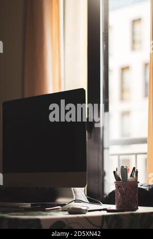 desk with computer and pens against window Stock Photo