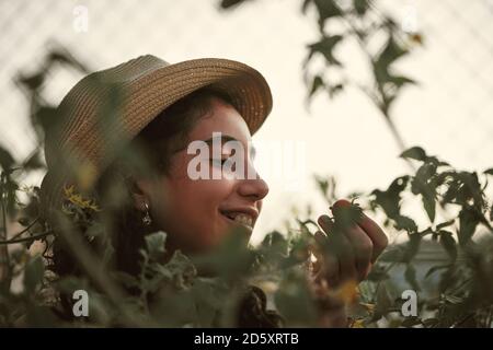 Close-up of a girl smelling a cherry tomato in the garden. Orchard concept Stock Photo