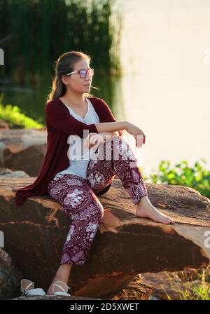 A woman sat on the rock at lakeside