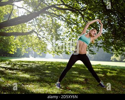 Germany, Young athletic woman doing sports, stretching exercise Stock Photo