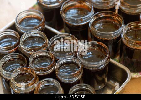 Open topped jam jars filled with setting dark liquid quince jam jelly homemade conserve Stock Photo