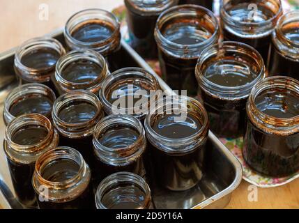 Open topped jam jars filled with setting dark liquid quince jam jelly homemade conserve Stock Photo