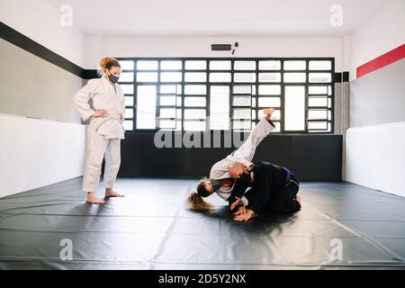 Three partners in a martial arts training such as judo or karate with kimonos practicing techniques on the gym mat all wearing face masks due to the c Stock Photo