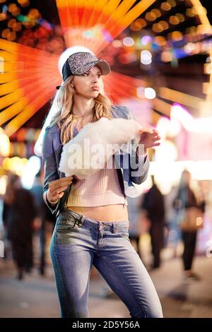 Young woman at fun fair eating candy floss Stock Photo