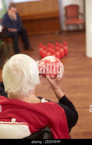 Age demented senior woman bowling with foam ball in a nursing home Stock Photo