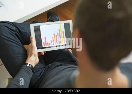 Businessman analyzing bar chart on tablet in office Stock Photo