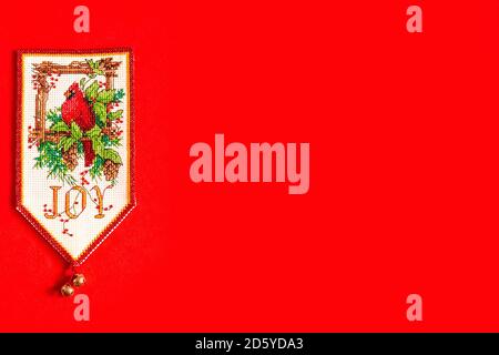 Christmas background with embroidered new year flag on red background, holiday, new year and Christmas concept. holiday. Christmas bird on a pine Stock Photo