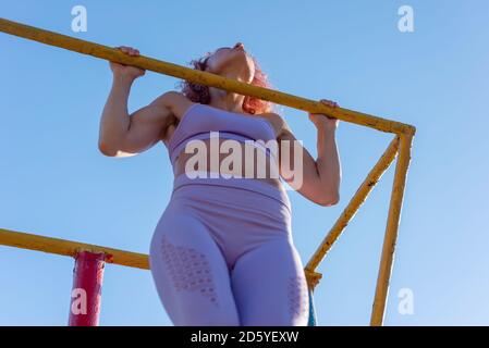 Woman pull-ups herself up on bar on sports ground in park Stock Photo -  Alamy