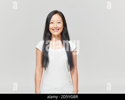 Portrait of smiling woman with long black hair wearing white shirt Stock Photo