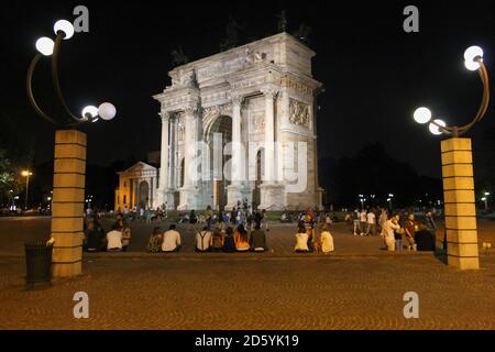 Milan - Italy ,July 12, 2014 : People talk and rest in Arch of Peace or triumph, historical city gate in Sempione Park, Milan. Stock Photo