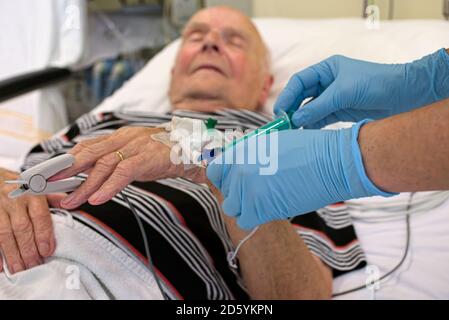 Taking of a blood sample from senior man being in intensive care after heart attack