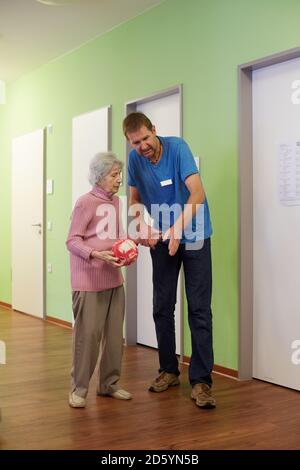 Geriatric nurse talking to age demented senior woman with foam ball  in a nursing home Stock Photo