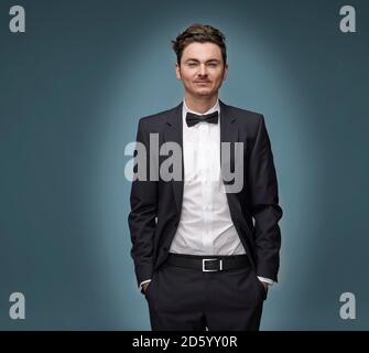 Portrait of arrogant looking man wearing suit and bow tie Stock Photo