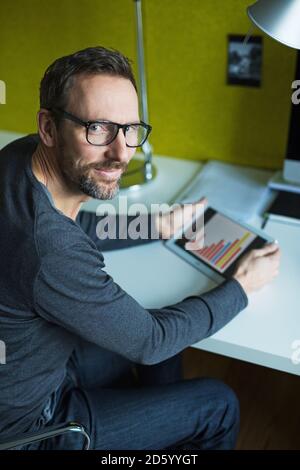 Portrait of confident businessman using tablet at desk in office Stock Photo