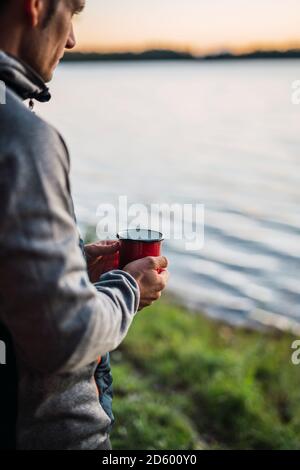 Man looking at the lake, drinking coffee Stock Photo