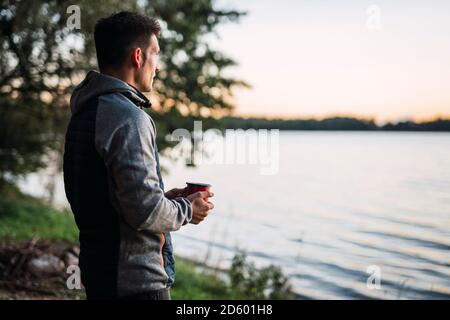 Man looking at the lake, drinking coffee Stock Photo