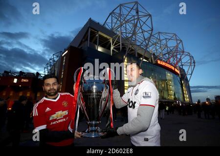 Manchester United fans pose with a replica UEFA Champions League trophy outside the ground before the game Stock Photo