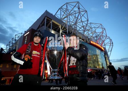 Manchester United fans pose with a replica UEFA Champions League trophy outside the ground before the game Stock Photo