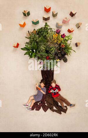 Boy and girl sitting under the tree Stock Photo - Alamy