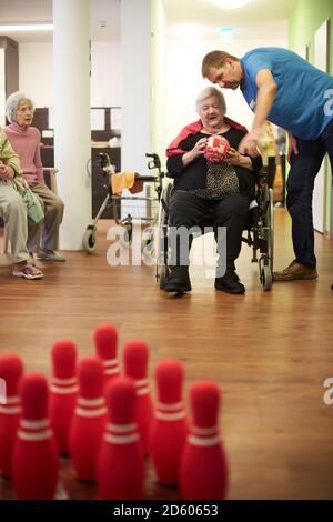 Geriatric nurse talking to age demented senior woman with foam ball in a nursing home Stock Photo