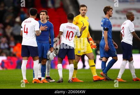 England's Kyle Walker (left) and Italy's Federico Chiesa exchange words as England's Raheem Sterling and Jack Butland shake hands after the final whistle Stock Photo