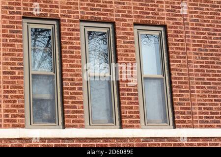 Vintage reddish brown brick wall texture background with rough textured bricks and three tall windows Stock Photo