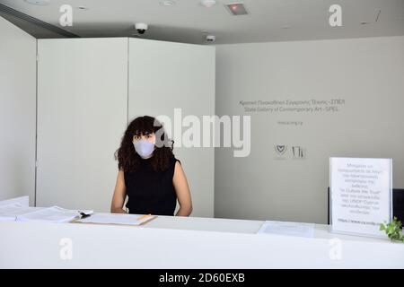 Young woman wearing face mask for covid precautions at reception desk in “State Gallery of Contemporary Art”, Pafos, Cyprus Stock Photo
