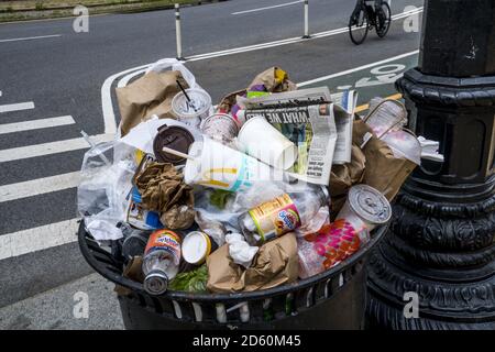 Overflowing trash can on Cortelyou Road in Brooklyn, New York. One time use containers creates the huge amounts of garbage around the US and more and more around the world. Stock Photo