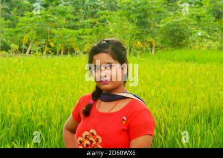 Close up of a Teenager girls wearing traditional Indian dress in an agricultural field with green paddy rice, selective focusing Stock Photo