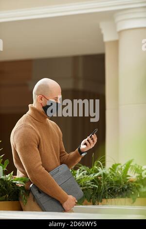 Mature man in mask using his mobile phone Stock Photo