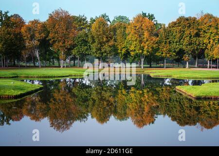 Row of trees with colorful leaves is reflected in the water in the park of Schwerin castle on a sunny autumn day, copy space, selected focus Stock Photo