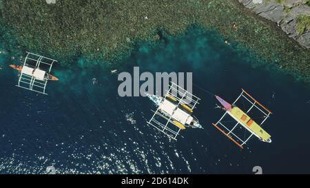 Top down of boats at green mount ocean coast aerial view. Epic summer landscape with vessels at rock shore. Nature beauty of tropic mountain isle Palawan, El Nido Islands, Philippines, Asia. Stock Photo