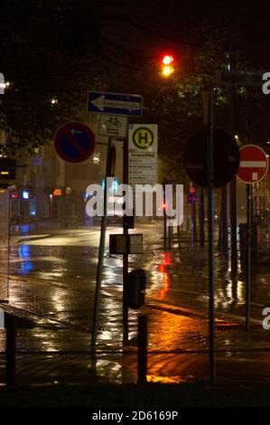 Rainy night in the big city, cars driving on street. Defocused image. traffic lights and many street signs in the foreground. Stock Photo
