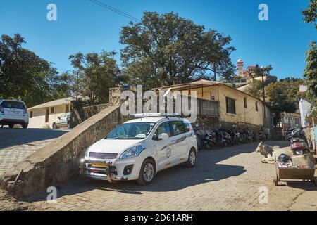 Tourist taxis and cows wait in between the streets and houses of Mount Abu, Rajasthan, India Stock Photo