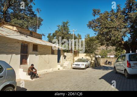 Man waiting outside his house in Mount Abu, with tourist taxis parked around him. Stock Photo