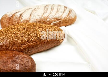 Various kinds of bread on white fabric surface. View from above Stock Photo